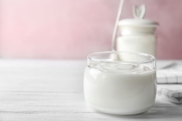 Glass jar tasty with yogurt on wooden table