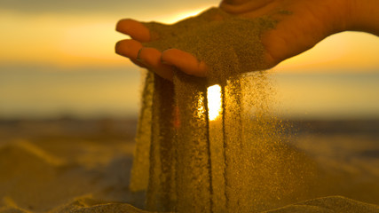 CLOSE UP: Unrecognizable woman grabs a handful of dry sand and lets it fall. - obrazy, fototapety, plakaty