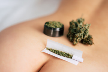 joint weed Cannabis buds on the girl's ass grinder rolled marijuana. The concept of sex and marijuana. themed weed and sex