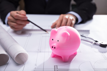 Close-up Of Piggy Bank On Blueprint