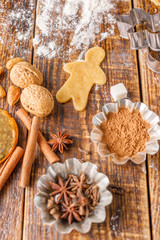 Ingredients and molds for the preparation of classic ginger biscuit figurines of little men on a wooden table.
