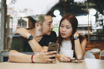 Couple using a phone at a cafe