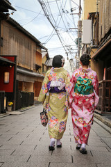 Fototapeta na wymiar Women in traditional dress that call kimono, are walking on the stone pavement in culture street at Gion, Kyoto, Japan.