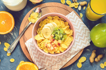 Delicious and healthy breakfast, top view. Milk, corn flakes, orange juice, orange, apple, nectarine, kiwi, banana, peanuts