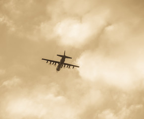 Fototapeta na wymiar vintage bomber flies into the clouds at sunset in sepia
