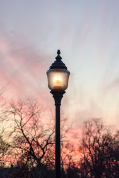 single streetlamp glowing at sunset in park
