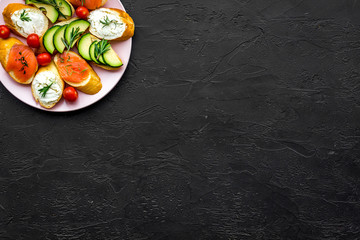 homemade sandwiches with french baguette, salmon, cheese and vegetable on black background top view mock-up