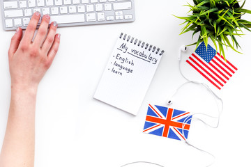 Learn english concept. British and american flags, computer keyboard, notebook for new vocabulary on white background top view copy space