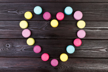 Bright almond cookies laid out on a dark wooden background in the form of heart