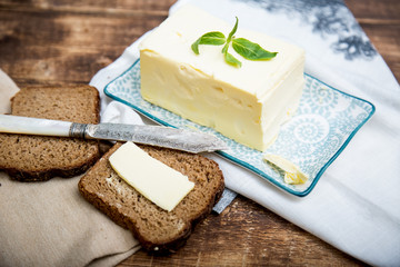 A piece of bread with butter on wooden background