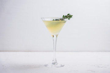 Tasty bitter cocktail with thyme in martini glass. Selective focus.
