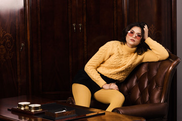 Obraz premium Portrait of a stunning fashionable model sitting in a chair in retro style