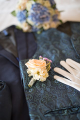 Man groom suite, vest, tie, belt, watch, bouquet flower, swan towel lying on a bed for preparation on wedding day