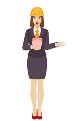 Businesswoman in construction helmet with piggy bank gesturing.