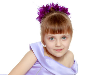 Girl sits on the floor with her hands folded in front of her.