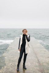 Pretty young woman stands on the wet from the water pier.