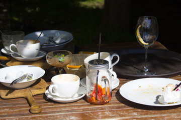 After the outside meal, table set with an empty eaten food plate, cutlery, empty bread basket and various dishes, selected focus