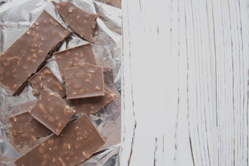 chocolate pieces on foil on wooden table, copy space
