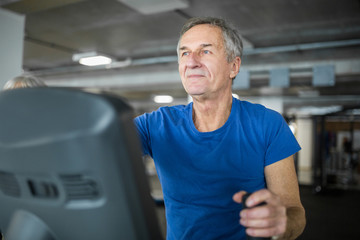 Happy senior man exercising on stair stepper at gym