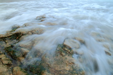 Blurred sea waves over rock on a shingle beach on the Jurassic Coast in Devon