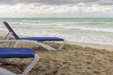 Fototapeta na wymiar Empty chaise lounges on the background of a deserted sea, the en