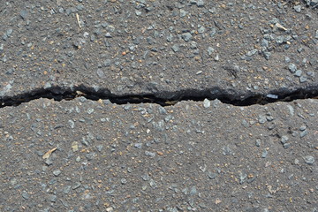 crack in grey pavement on the road