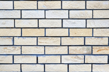 Obraz premium Brick wall of light beige and yellow brick. Smooth a few rows of bricks. Laying overlap. The surface is rough and rough. There are small blue paint stains in some places. Background or texture.