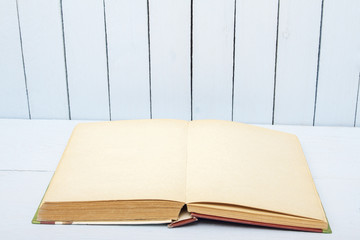 Open book on background woodens table and wall. Blank pages fo copy space or text