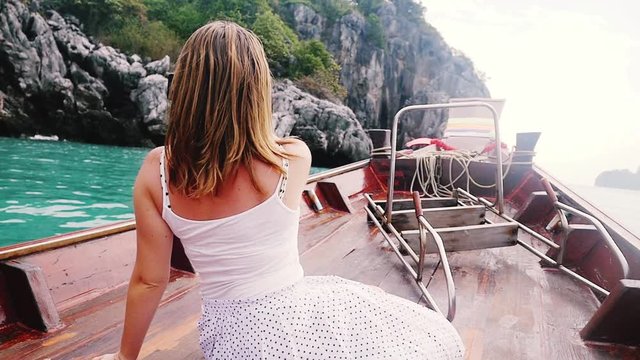 Traveler woman looking destination island and relaxing on wooden boat.Girl taking picture with mobile phone on long tail boat, wind blowing her hair. slow motion. 1920x1080