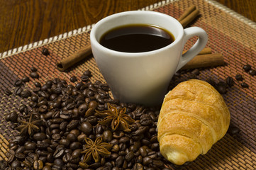 White cup of coffee with cinnamon and croissant
