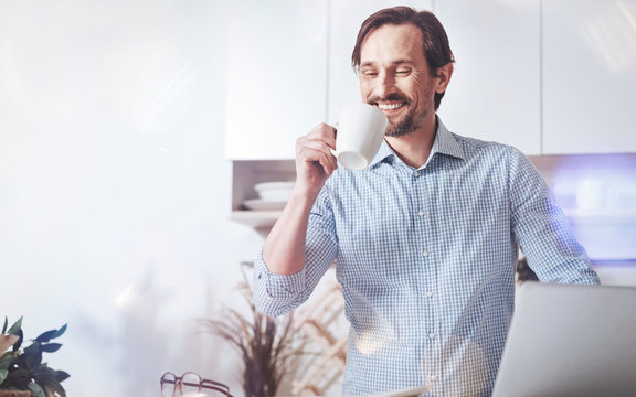 Pleasant Morning. Cheerful Delighted Man Drinking Coffee And Enjoying Time While Getting Ready To Go To Work