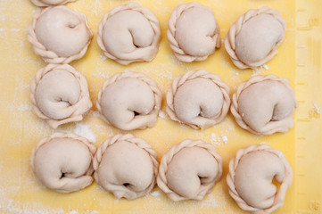 Fototapeta na wymiar Raw dumplings lie in rows on a silicone yellow board top view
