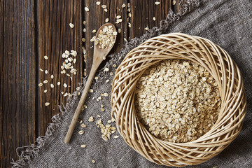 Close-up photo of Oat Flakes in wooden plate with spoon on scarf on wooden background