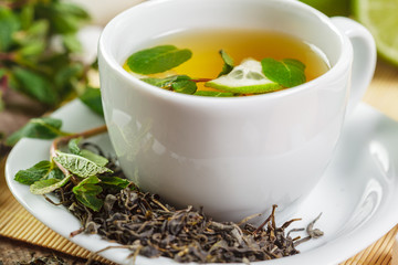 cup of black tea with mint leaves on a wooden table