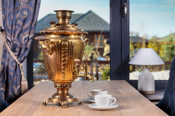 ancient samovar stands on an oak table on the background of the window
