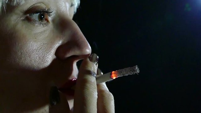 Woman   with cigarette . Slow motion .Black background