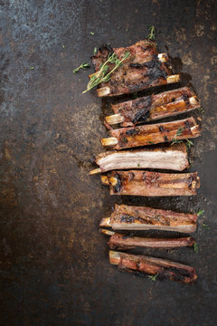Barbecue spare ribs St Louis cut with hot honey chili marinade sliced as top view on an old rustic board