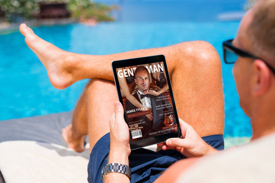 Man reading emagazine on vacation by the pool