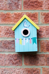 Blue small cue wooden bird house hanged on brick wall