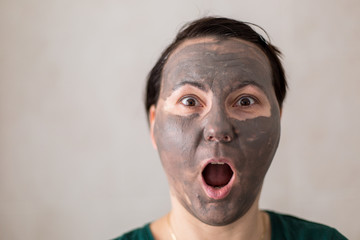 Young adult woman with grey cosmetic mask on face