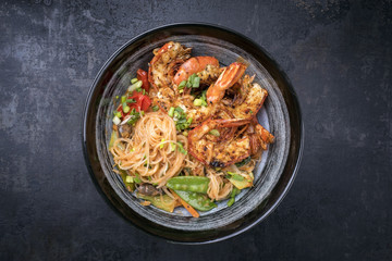 Traditional Thai Phak Kung curry with barbecue king prawns and noodles as top view in a bowl © HLPhoto