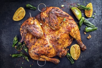 Foto op Plexiglas Spatchcocked barbecue kip al mattone met groente als bovenaanzicht op een oud bord © HLPhoto