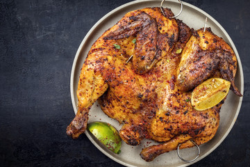 Traditional spatchcocked barbecue chicken al mattone with lemon slices as top view on a plate with...