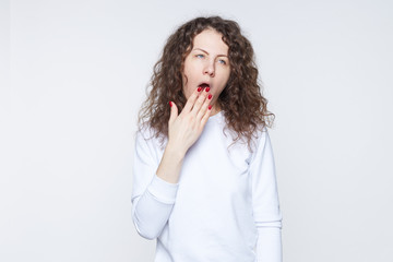Tired or bored young American woman covering mouth while yawning, feeling exhausted after hard day...