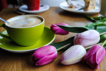 Fototapeta na wymiar A cup of coffee and a bouquet of tulips