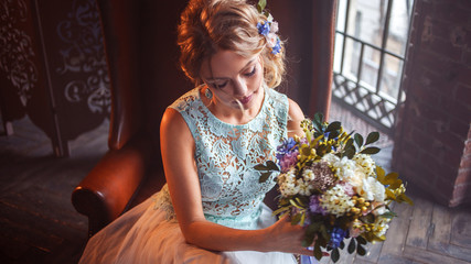 Young beautiful woman in wedding dress with bouquet of flowers. Wedding hairstyle, flowers in hair.