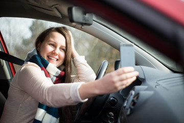 Fototapeta na wymiar Pretty young brunette woman taking a selfie in the car