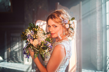 Young beautiful woman in wedding dress with bouquet of flowers. Wedding hairstyle, flowers in hair.