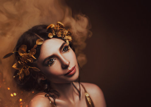 Close-up portrait. Girl with creative make-up and with golden eyelashes. The Greek goddess in a laurel wreath with flowers and handmade roses. Art Photo