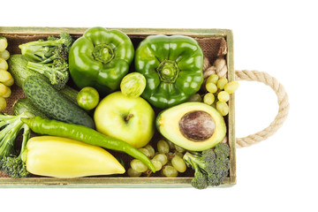 Set of different green fresh raw vegetables and fruits in the wooden tray